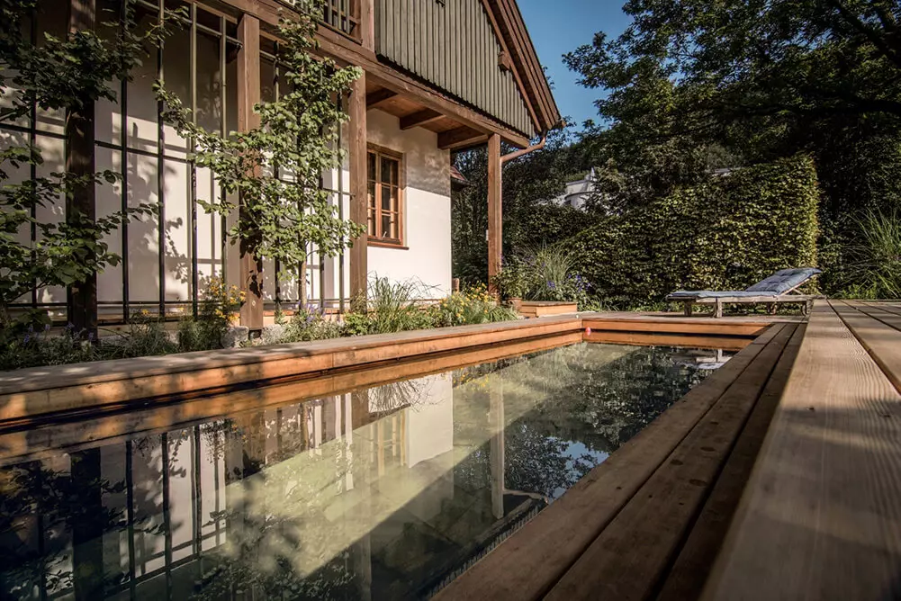 Showing a pool in front of a farmhouse by Holc Naturpools