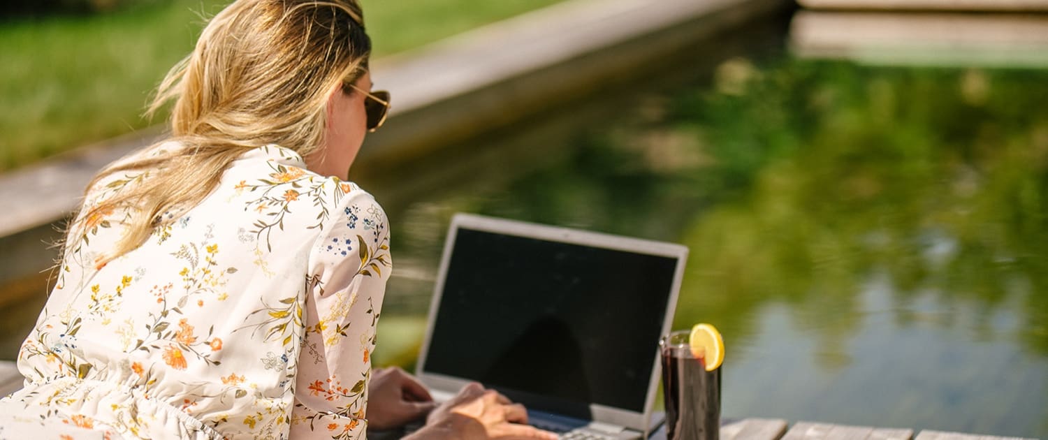 Damen sitzt mit Laptop am Holc Naturpool